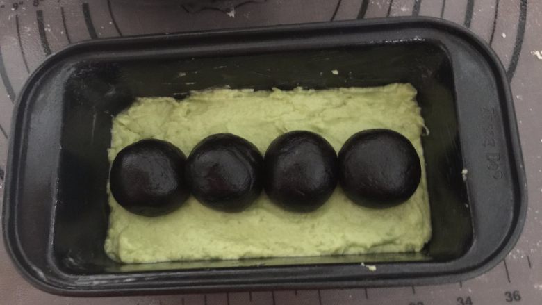 奥利奥牛油果磅蛋糕,接着排入4个黑色小圆球，也可以直接搓成圆柱体，我的面团太干容易裂开，所以分成4个小圆球（其实最好是搓成完整一个圆柱体）
