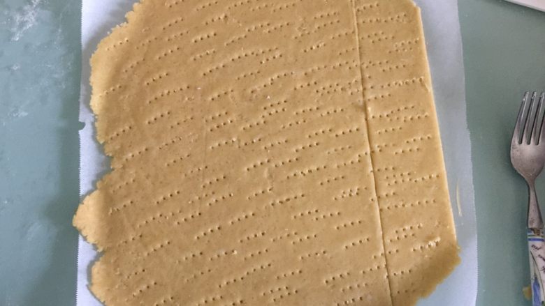 海苔咸味饼干,案板上撒一薄层低筋面粉或者上下各铺上一层油纸，把松弛好的面团放在案板上擀开成薄面片，用叉子在表面扎点小孔