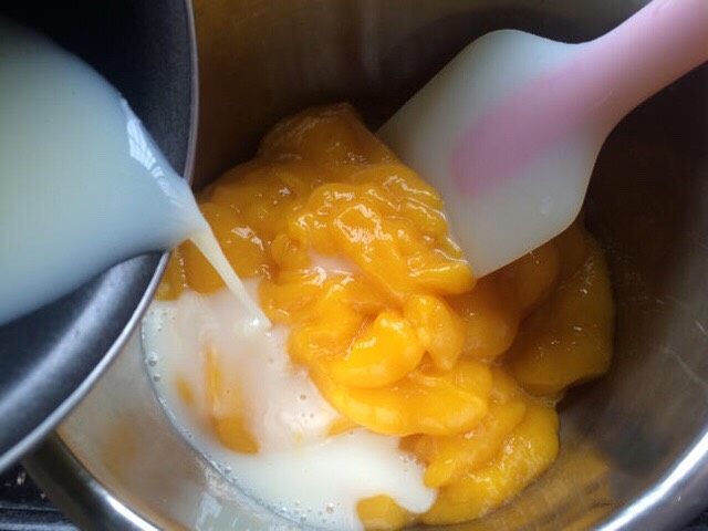 芒果酸奶冻,把吉利丁牛奶液倒入芒果泥中搅拌均匀。
