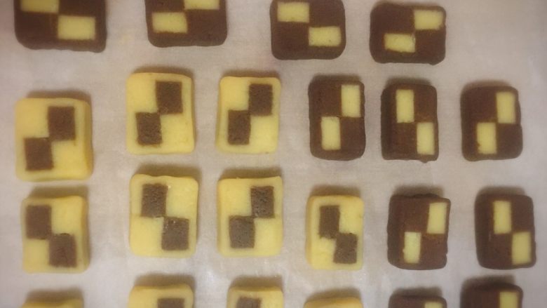 双色格子/棋盘饼干,同样的方法也把可可面团的边角料包裹格子条，切成片。还有一条格子条直接切片。把切片都放在铺了油纸的烤盘上