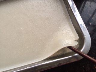 自制河粉,蒸好后把蒸盘取出，用筷子在蒸盘角的边边挑起。