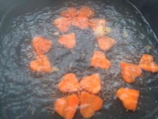 胡萝卜香葱爱心饼干,然后锅中放入适量的水大火煮开，再把爱心胡萝卜倒入大火煮5分钟左右。