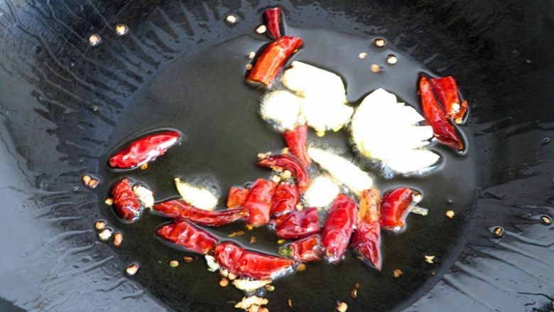 开胃酸辣西瓜皮,热锅注入油烧至6分热，下入蒜和红干椒爆香