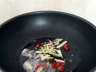 酱爆鱿鱼丝,炒锅中放入花生油烧热，放入辣椒，姜丝，蒜片小火呛锅。