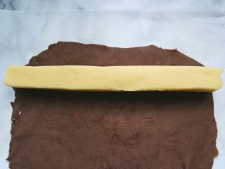 辛巴小饼干,翻转硅胶垫与油纸，并揭去硅胶垫，取出冻好的原味面团放在可可面饼上