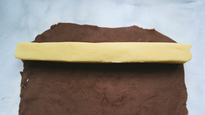 辛巴小饼干,翻转硅胶垫与油纸，并揭去硅胶垫，取出冻好的原味面团放在可可面饼上