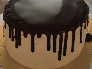 巧克力淋面蛋糕,裱花袋剪开一个小口，在事先抹好奶油的蛋糕表面快速来回淋，速度要快。不用担心涂不平，巧克力液会往边缘散开，自然就平了，然后在蛋糕边缘快速淋一圈巧克力液。因为蛋糕是冷的，又有吉利丁片起到凝固作用，所以巧克力液很快就会凝固，这样淋面就完成了。
