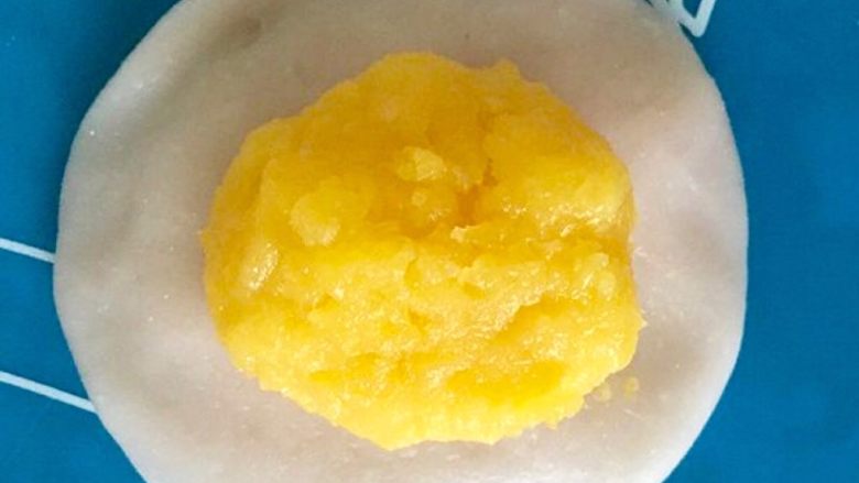 Q弹奶黄冰皮月饼,冷却好的奶黄馅平均分成12个奶黄馅团，将一个奶黄馅团包进冰皮里。（整体大概50g，刚好用50g的月饼模具）