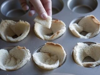 培根，鸡蛋和烤面包杯,将两面面包放入每个松饼杯中，一半应稍微重叠。使用剩下的面包填补任何空白