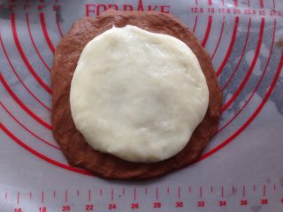 可可麻薯软欧包,将可可面团和麻薯团擀成圆形，麻薯团擀得比可可面团小一点，放在可可面团上面。