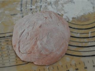 苋菜汁桃花包,将发酵好的面团取出，放在撒了面粉的案板上，排气