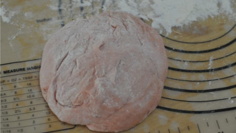 苋菜汁桃花包,将发酵好的面团取出，放在撒了面粉的案板上，排气