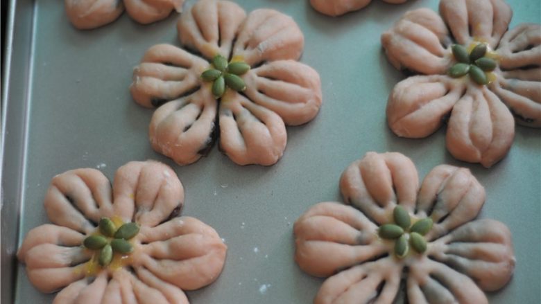苋菜汁桃花包,将南瓜籽在中间摆成花心状，发酵至两倍大