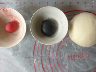 企鹅馒头,取30克面团加入适量的竹炭粉，和成黑色面团。取十克面团加入红曲粉，和成红色面团。