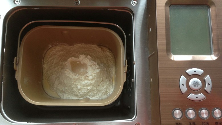 香蕉吐司,在面粉顶端加入酵母，面包桶放入面包机内。