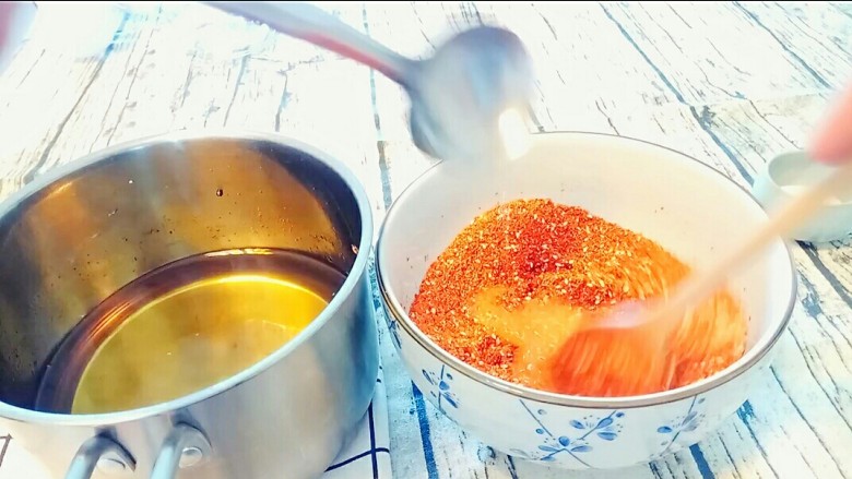 自制油辣子,先用小勺往辣椒面泼3勺油，趁热搅匀辣椒面。
