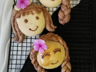 女孩花样面包#面团的发酵之旅#,巧克力提前装裱花袋隔水融化，裱花袋剪小口装饰自己喜欢的表情图案。