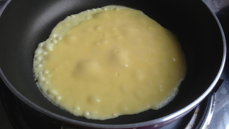 虎皮三明治,不粘锅里放一勺蛋奶糊，中小火煎大概一分钟，表面起很多泡泡，翻面。