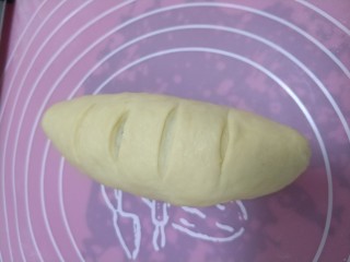 坚果面包#面团的发酵之旅#,从一端卷起，整形成橄榄球状，捏紧收口，用锋利的刀在上面切几个小口子