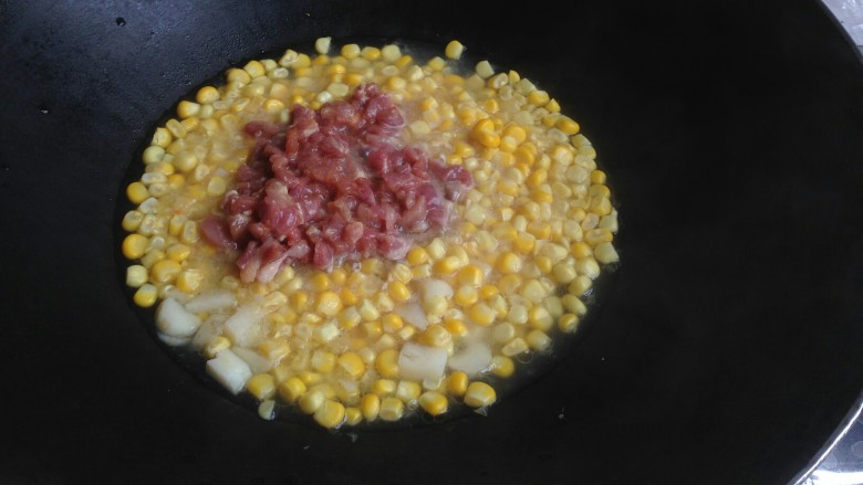 玉米青红椒炒肉丁,加入瘦肉丁炒一下，盖上锅盖煮五分钟左右。