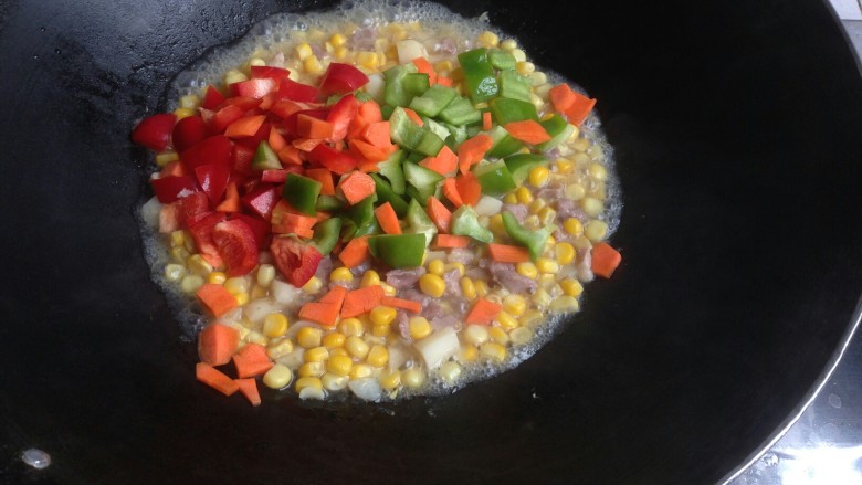 玉米青红椒炒肉丁,加入青红椒丁，胡萝卜丁，煮一两分钟。