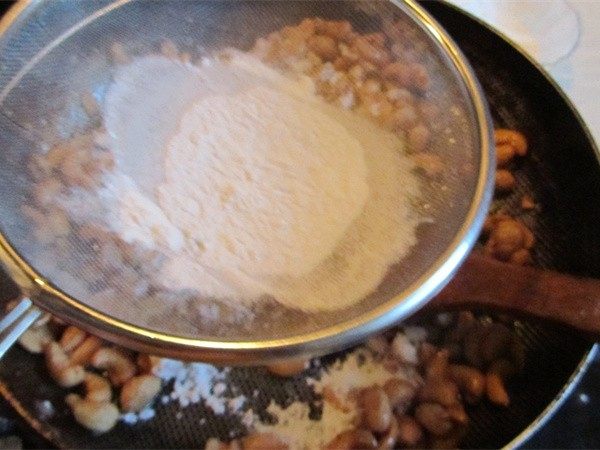 挂霜腰果,一边用锅铲快速地翻动一边用漏勺筛入淀粉；