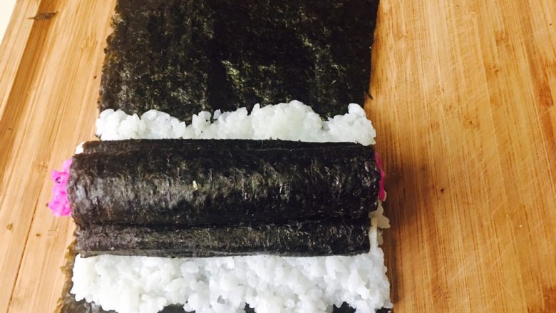 童趣寿司,这时就可以做组合了。取一张没裁剪过的紫菜，宽度同山药同宽。把米饭铺满1／2。放两根卷好紫菜的山药，再把卷好的红色饭团放上面，再卷起来即可。