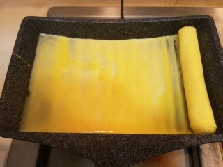 樱花玉子烧,把卷好的蛋卷移到锅子左边，再继续煎第二层，按此方法一共卷三层。