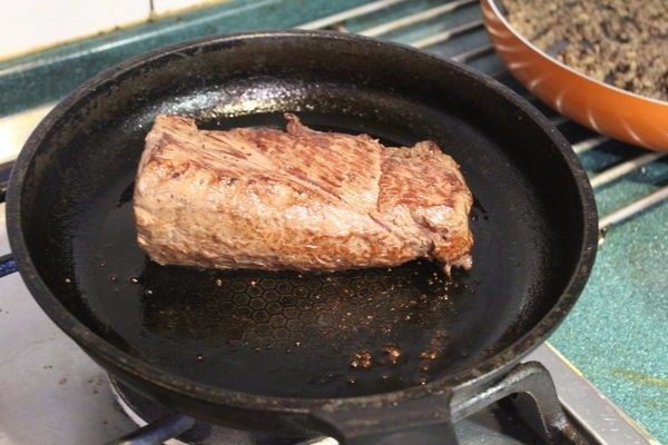 惠灵顿牛肉,平底锅大火烧热后，加一些橄榄油，菲力抹上些许盐和胡椒，每面煎1-2分钟，煎出焦色，熄火后，牛肉继续放在锅中备用。