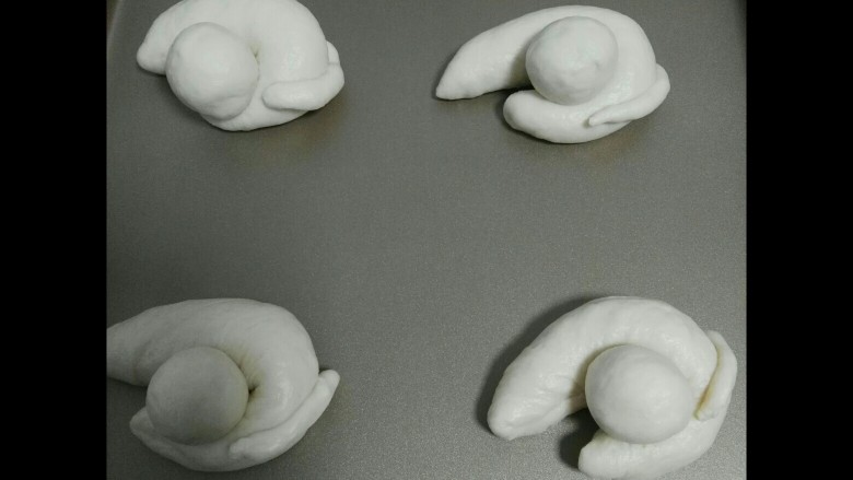 小猫面包,如图所示放上头和尾巴（可以刷很少的水沾好）放入烤盘用手稍微整理下，盖保鲜袋二次发酵。