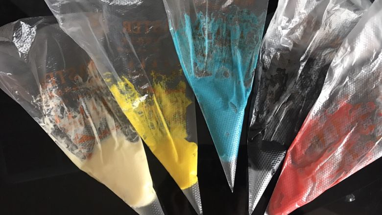 哆啦A梦彩绘蛋糕卷,面糊按照颜色多少分成五份调色，黑色描边部分用竹炭粉调色，白色部分用原色，其余用色素调色，装入裱花袋。