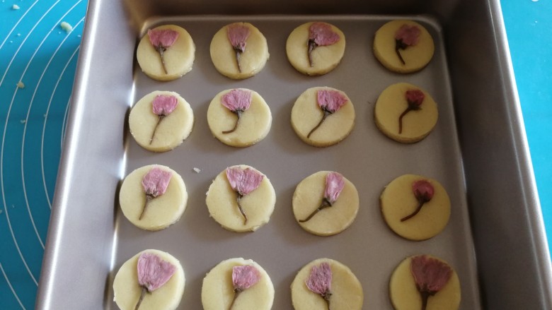 樱花曲奇饼干,用圆形模具按压，然后放入烤盘里面，轻轻的将樱花按压到面团上面。