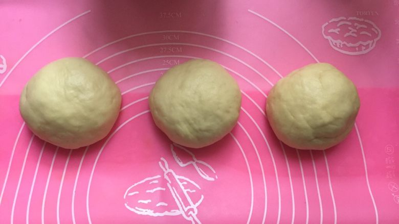 奶香土司面包#面团的发酵之旅#,把面团的空气排出，分成均匀的三等分，揉成圆形，盖上保鲜膜，放置15分钟