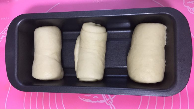 奶香土司面包#面团的发酵之旅#,整齐的放入吐司盒中。吐司盒放在烤箱中，下面放一烤盘的热<a style='color:red;display:inline-block;' href='/shicai/ 156925'>水</a>，进行发酵。发酵到九分满从烤箱取出。