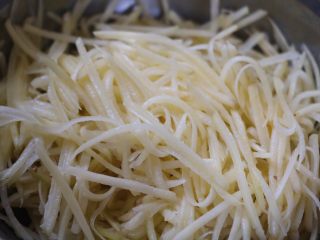 黑胡椒香肠烤土豆丝,取一个土豆，洗干净，去皮，用切菜器切成细丝。