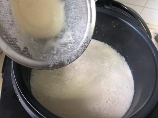 自制爽滑豆花,现在把熟豆浆倒进电饭锅里。
这时候可以再过滤一遍，倒的时候要缓缓的倒进，目的就是让豆浆和刚刚融化的内酯充分的融合在一起。