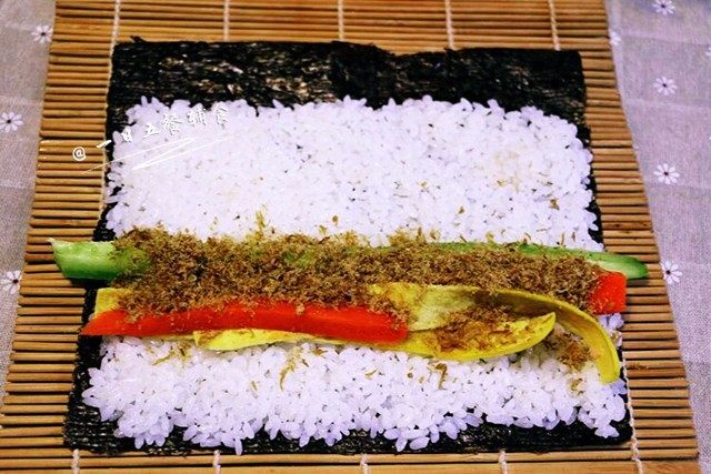 家庭寿司,铺好海苔，毛面朝上，铺满米饭，最尾端留点位置，否则一会卷的时候米饭会冒出来。放入<a style='color:red;display:inline-block;' href='/shicai/ 54'>黄瓜</a>、胡萝卜、蛋皮、肉松卷起来，卷紧。