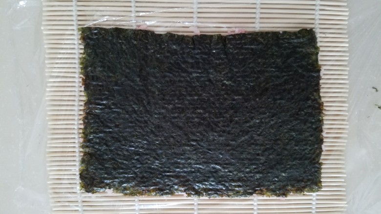 樱花寿司,压好后保鲜膜就粘在米饭上了，然后翻转过来，保鲜膜在下成，海苔在上面。