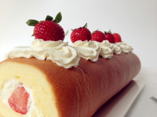 草莓蛋糕卷,借助擀面杖卷起蛋糕卷。在表面挤上淡奶油，放上草莓装饰即可。