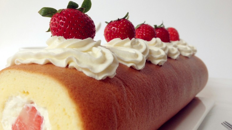 草莓蛋糕卷,借助擀面杖卷起蛋糕卷。在表面挤上淡奶油，放上草莓装饰即可。