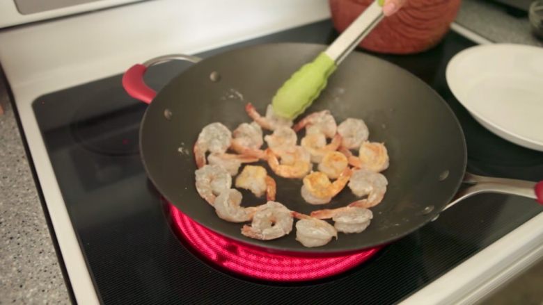 姜葱炒鲜虾,开大火，加入油，并旋转以覆盖锅底。当锅很热时，将虾倒入，两面煎至金黄