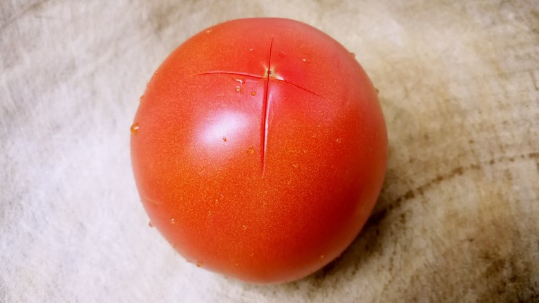 番茄鸡蛋牛肉粉,用刀在番茄底部划十字。