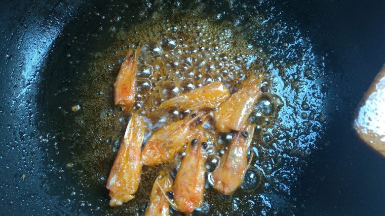 鲜虾仁焗饭,下入鲜虾头，一遍翻炒一般压挤虾头，煸出红油，捞出不用。