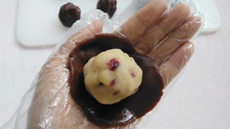 巧克力蔓越莓莲蓉月饼,戴上一次性手套，取其中一个面团用2个掌心的摩擦力按扁，放上莲蓉馅