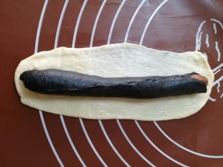 豹纹吐司,白色面团也擀成椭圆长条形面片，把竹炭的面团包起来，这里的收口要包好，不能露出黑色面团