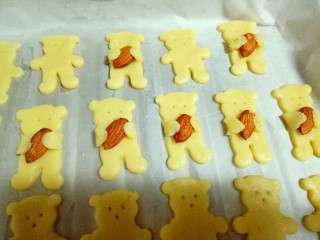 小熊抱杏仁饼干,小熊的手抱住杏仁就完成了，全部做完，烤箱170度预热5分钟，烤盘入烤箱中层，14 度上下火烤10-12分钟，(注意观察颜色，根据自家烤箱性能另设定温度。)