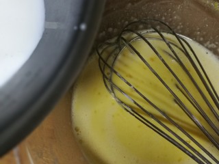 低卡南瓜蛋糕卷(内附无油低卡南瓜卡仕达酱做法),把煮沸的牛奶，一边沿蛋黄糊慢慢倒入，边倒边搅拌。