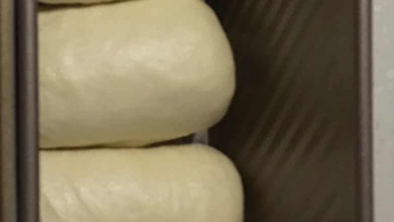 原味吐司,取出面团擀成椭圆形、再卷成卷均匀放入吐司模具里。