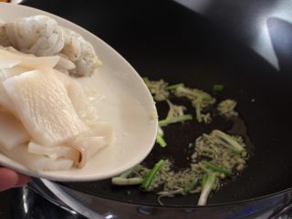 海鲜锅巴,
6.另起一炒锅，油热先下葱茎和姜，紧接着下鱿鱼和大虾。
