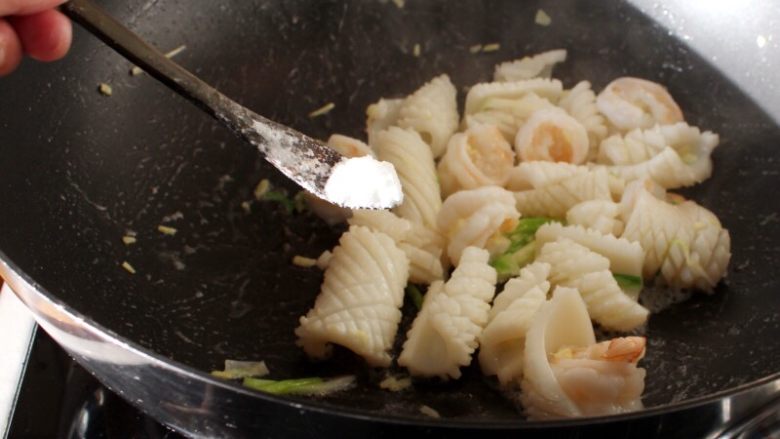 海鲜锅巴,7.炒到鱿鱼和大虾卷起加盐和白胡椒调味，盛出备用。
